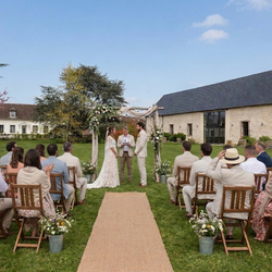 Cérémonie de mariage en plein air avec couple sous une arche et invités assis sur des chaises en bois.