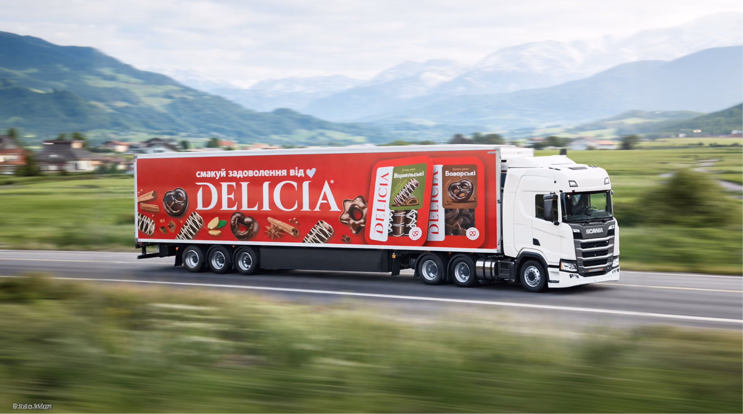 White Scania truck with red Delicia branded trailer decorated with chocolate pastries driving past green fields.