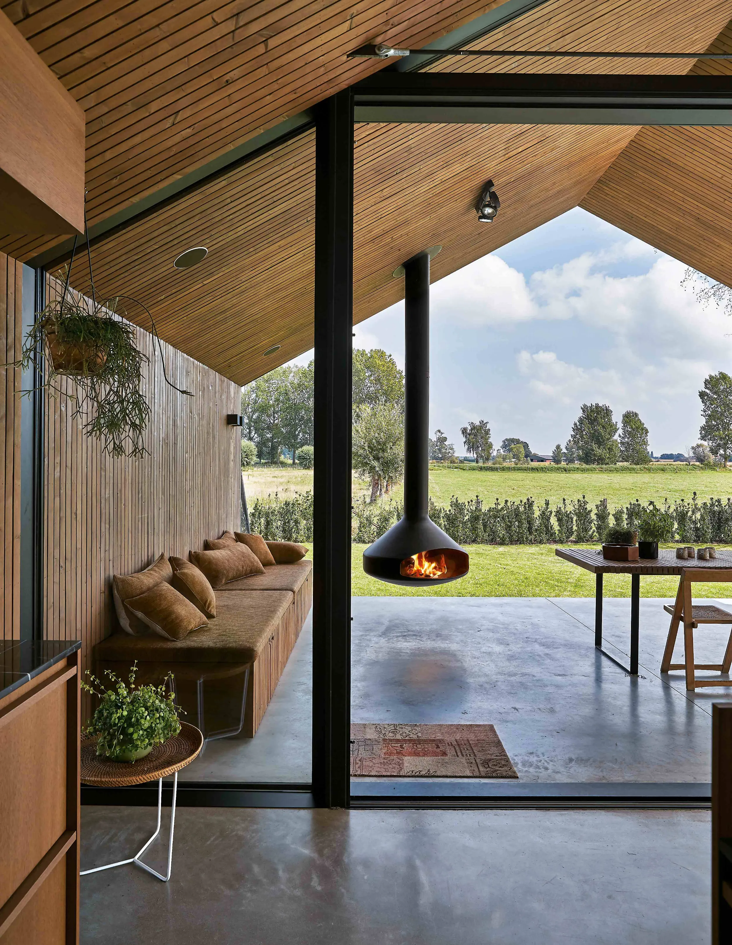 Ergofocus suspended outdoor wood-burning fireplace by Focus Creation with sculptural flowing form and open fire design