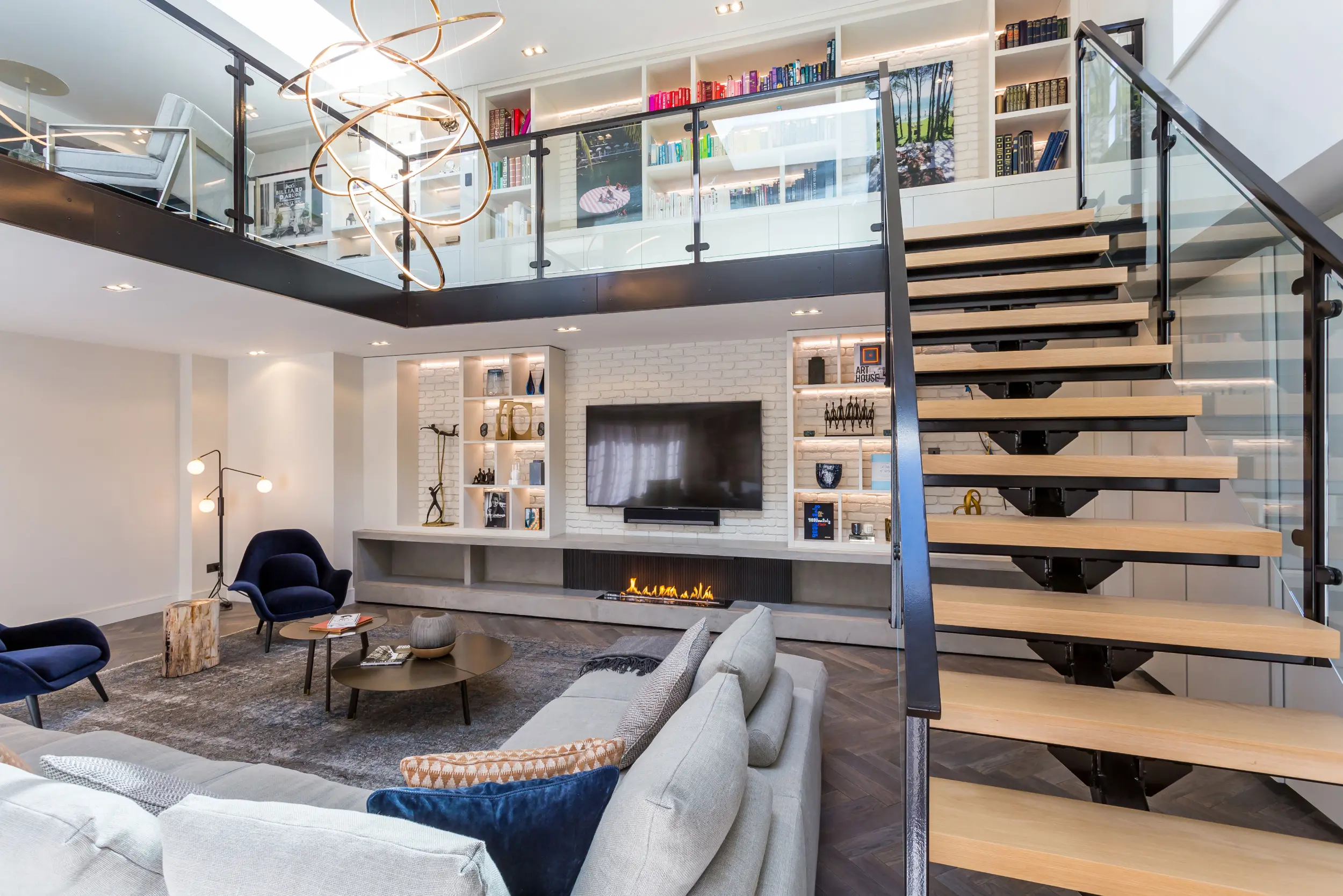 Modern three-sided bioethanol media wall fireplace with ribbed metal back panel, microcement base, bespoke joinery and integrated television. Angled view