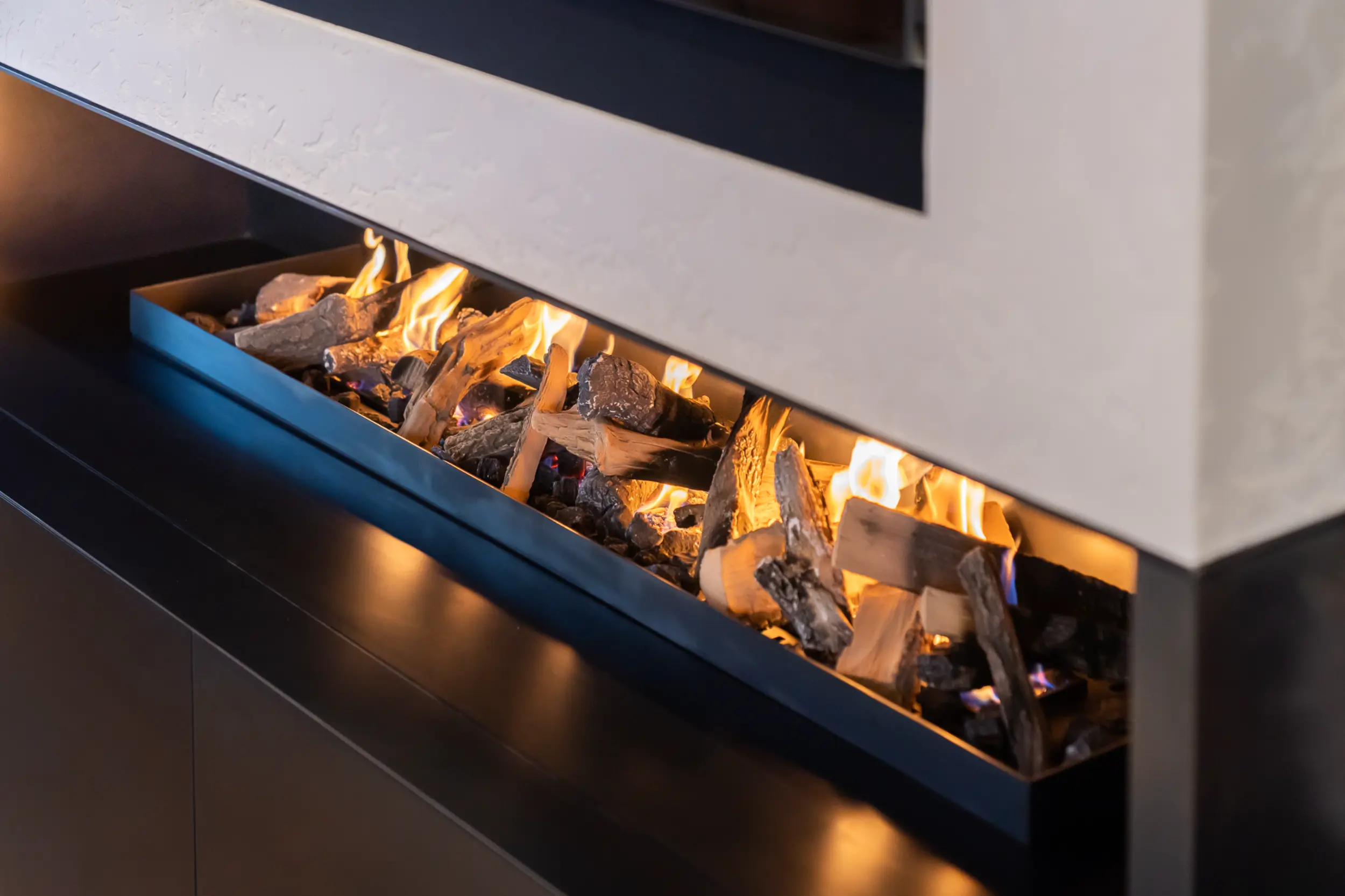 Side view of bespoke open-front gas fireplace with blue steel cladding integrated within contemporary penthouse media wall