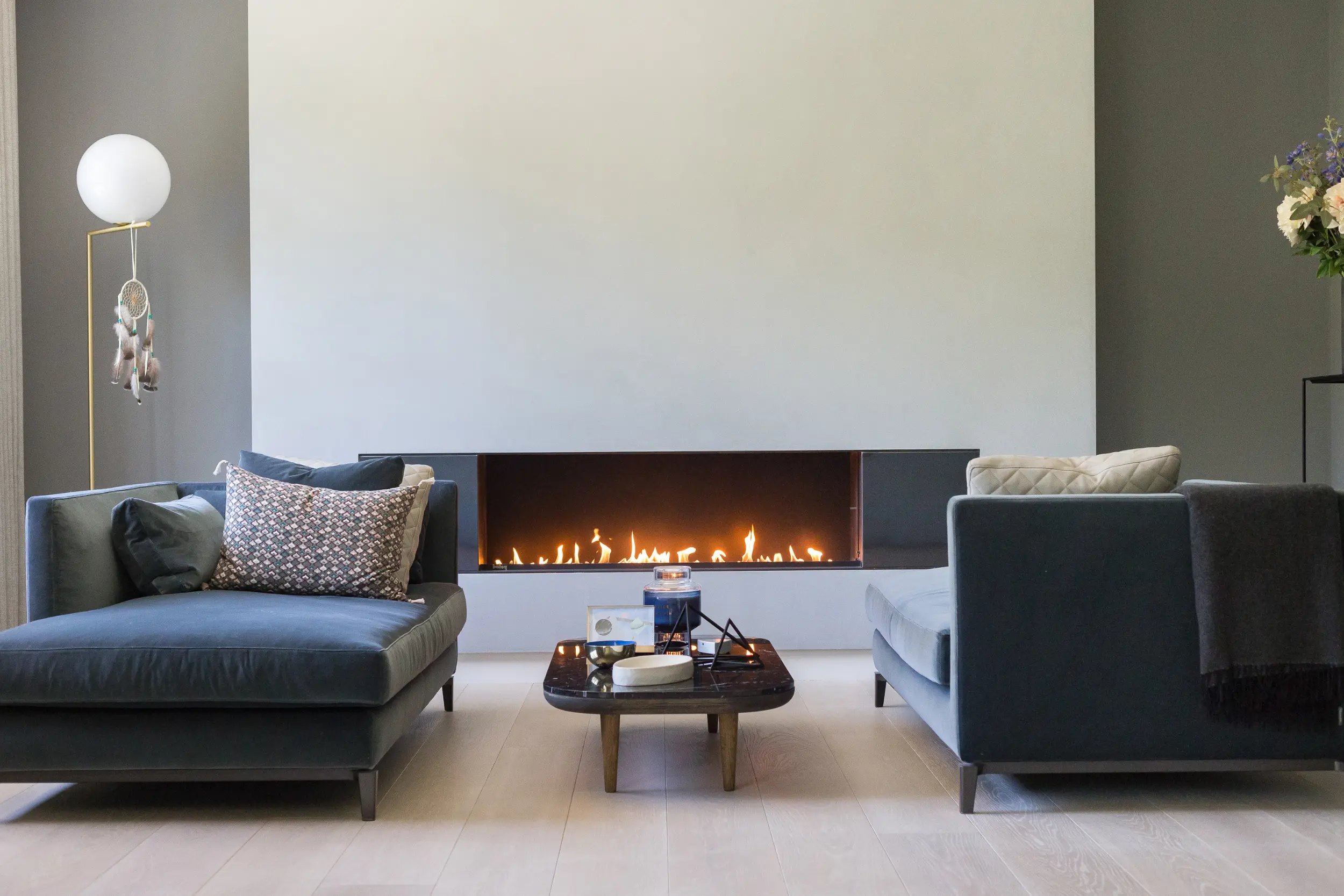 Close up of open-fronted line gas fireplace with bespoke side panels in luxury master bedroom suite