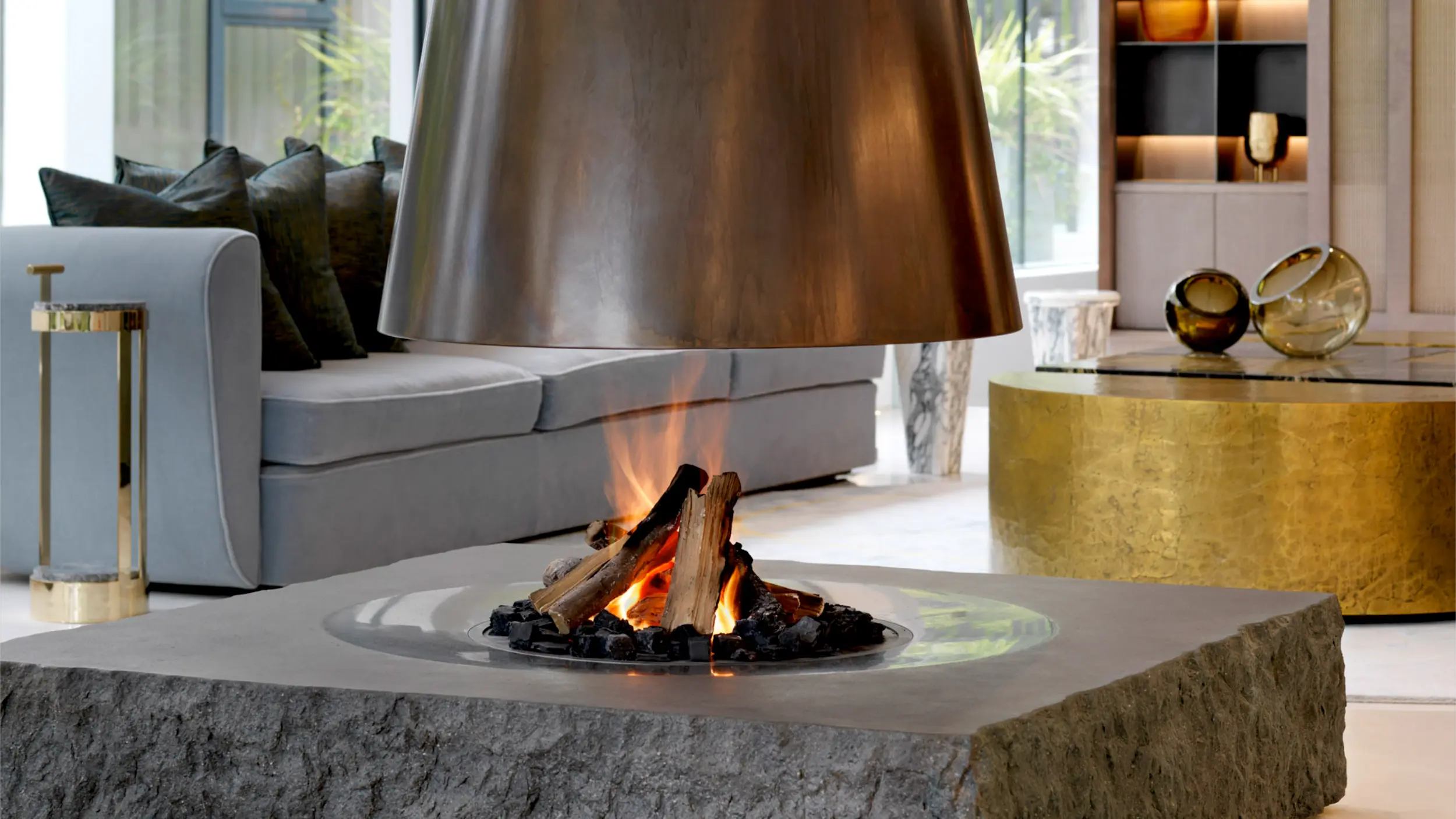 Bespoke aged brass suspended fireplace with lava stone base and lifelike log burner by Modus Fireplaces