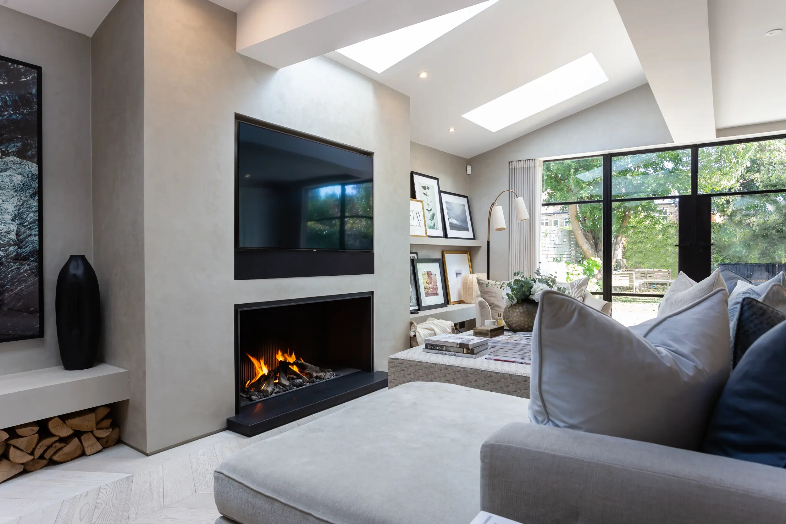 Bespoke flush-floor gas fireplace with black panelling integrated into a London townhouse media wall by Modus Fireplaces and Laura Hammett