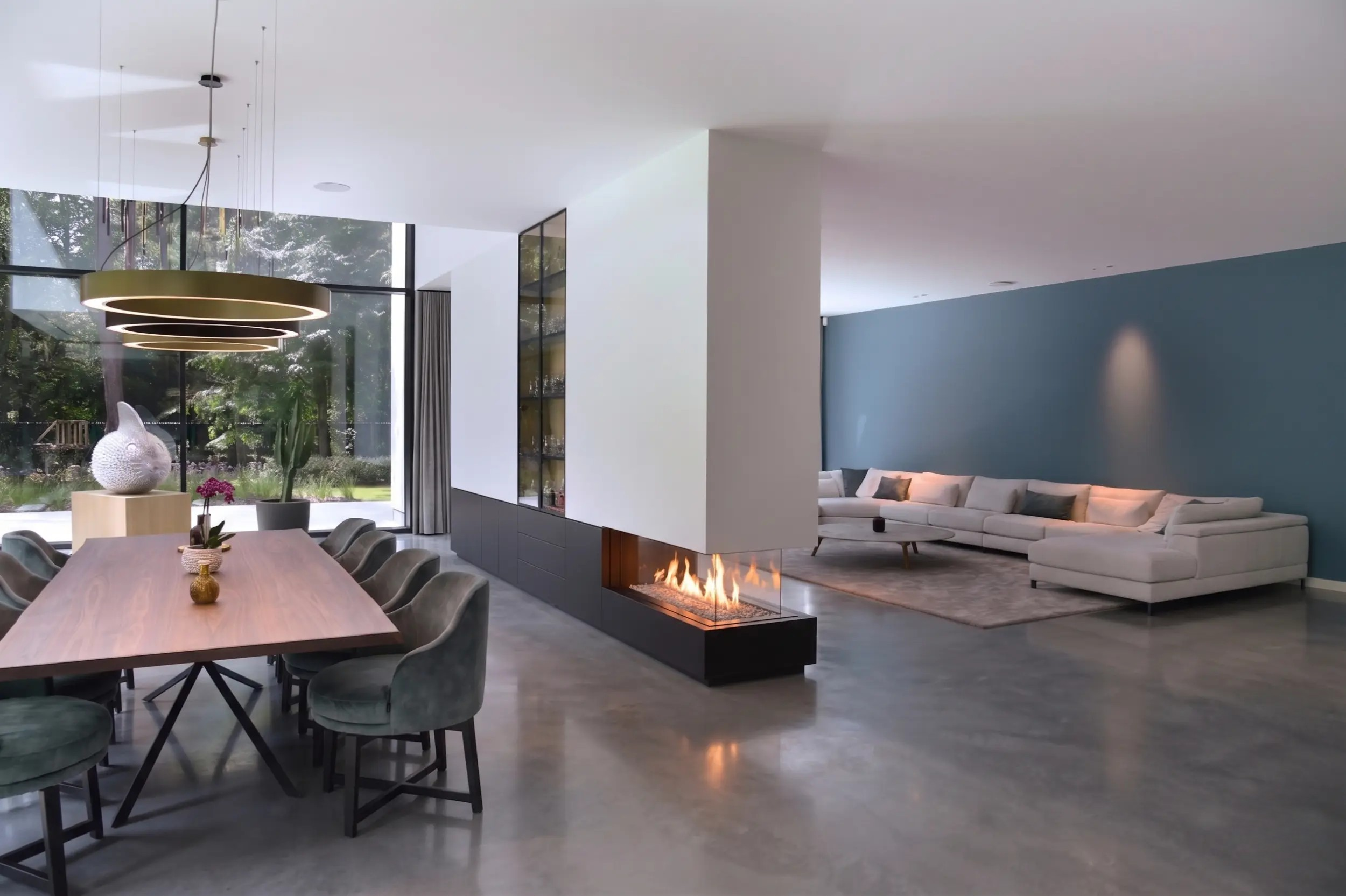 Three-sided glass room divider fireplace with stone flame-bed decoration between a lounge and dining room