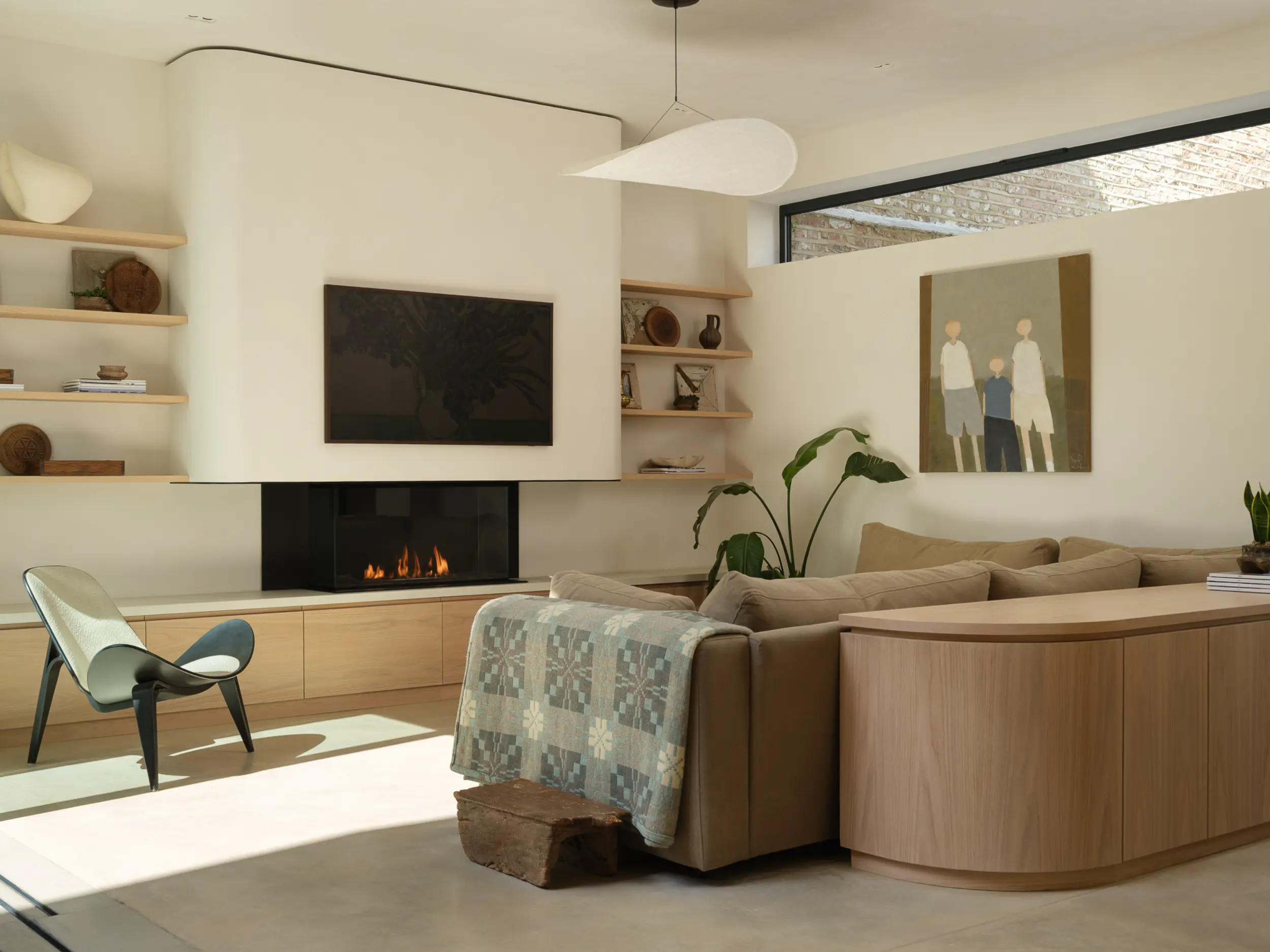 Glass fronted bioethanol fireplace set beneath curved plastered canopy in contemporary light filled living space