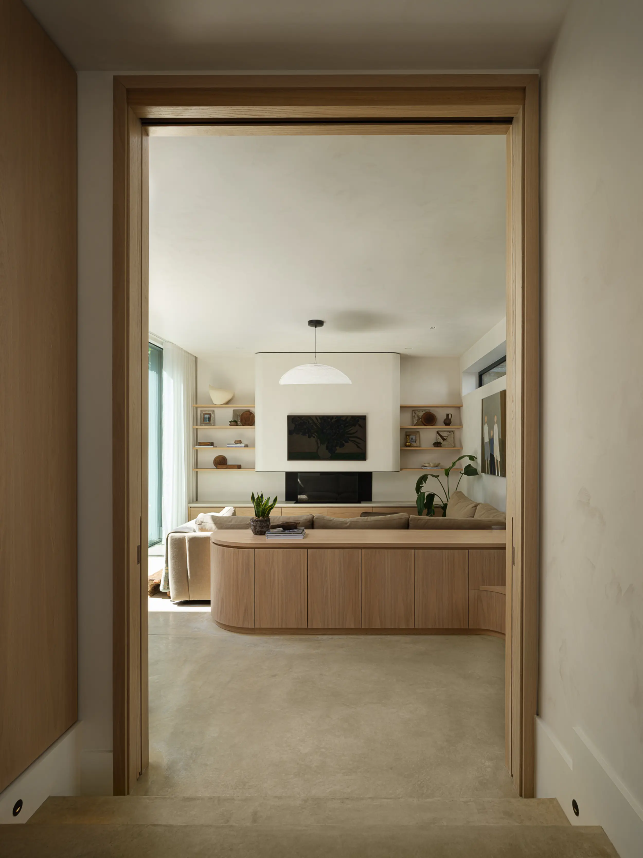 Glass fronted bioethanol fireplace set beneath curved plastered canopy in contemporary light filled living space by Modus