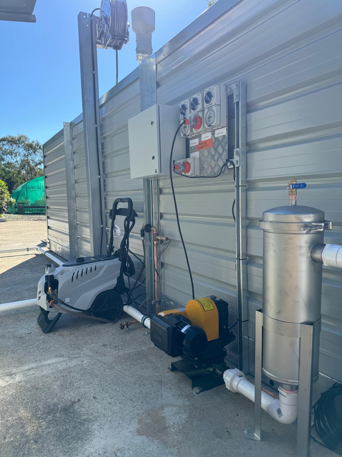 Washbay pump skid, pressure washer, controls and treatment equipment mounted beside washbay