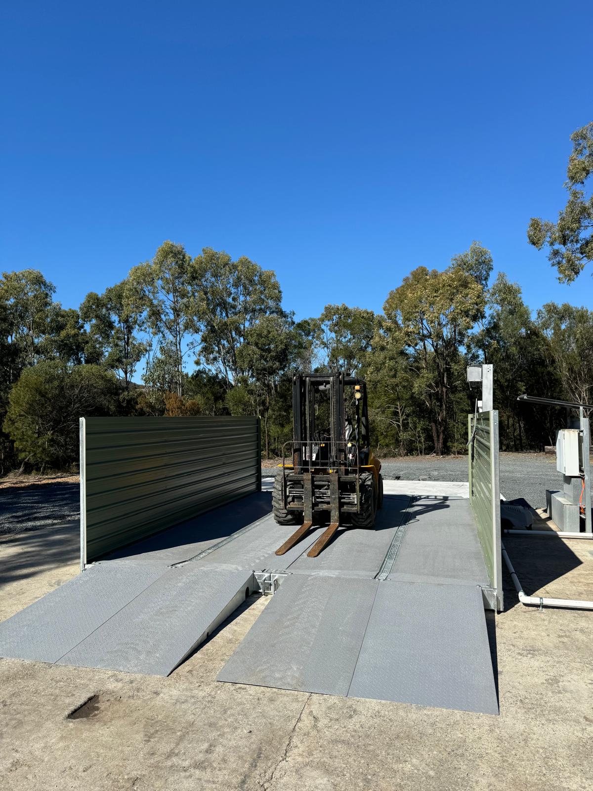 Forklift positioned inside modular washbay with side screens and ramps
