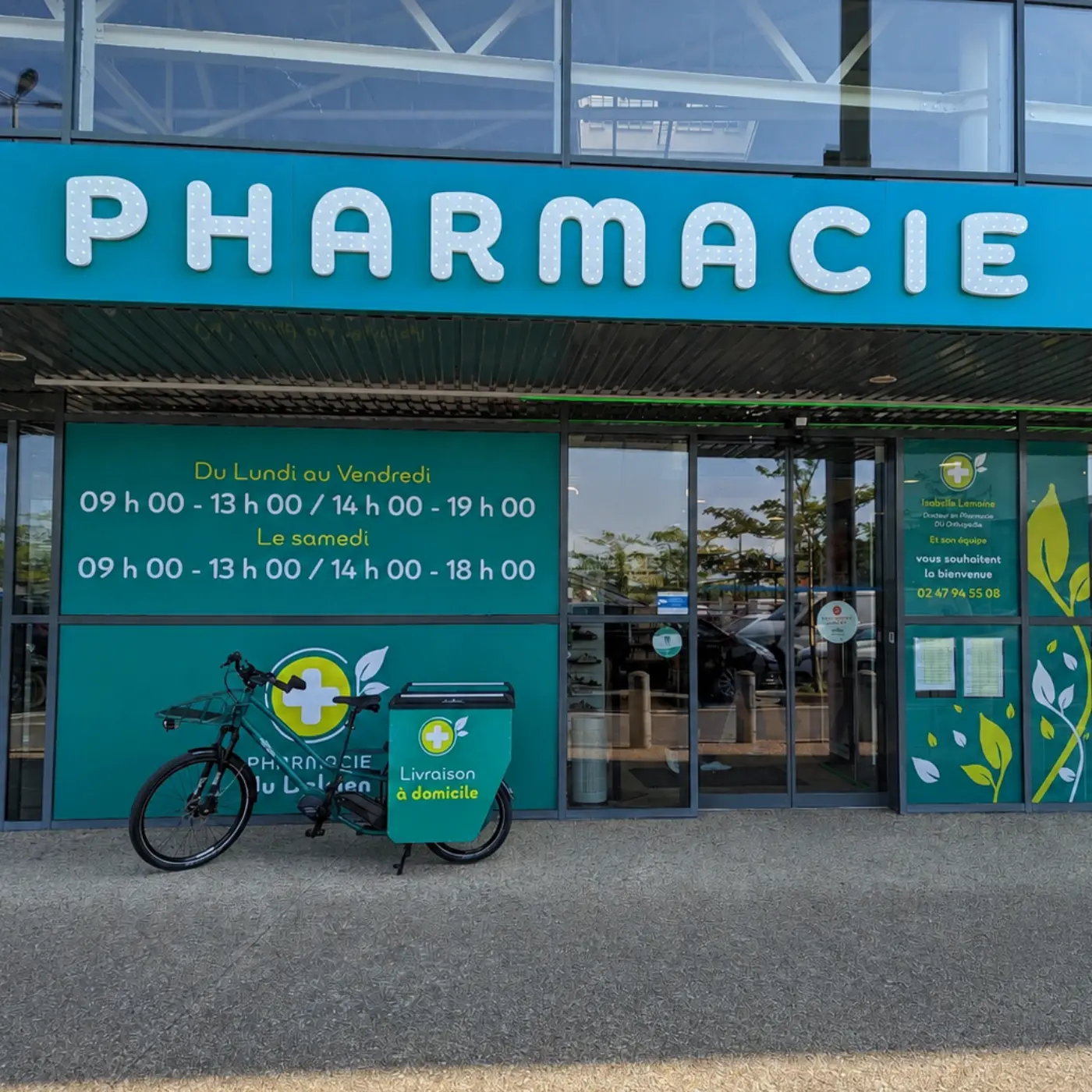 Devanture d'une pharmacie avec horaires et vélo de livraison à domicile garé devant.