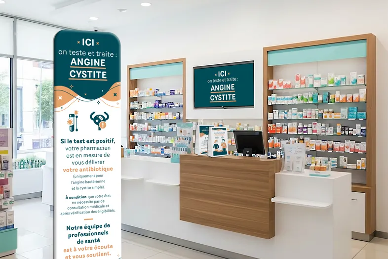Intérieur d'une pharmacie avec un comptoir en bois et un panneau indiquant traitement de l'angine et cystite.