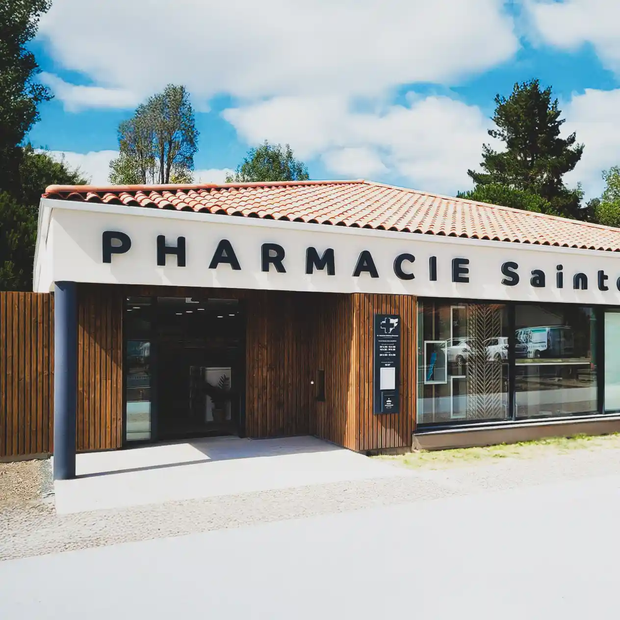 Façade moderne de la Pharmacie Sainte Flaive avec un toit en tuiles et des murs en bois.