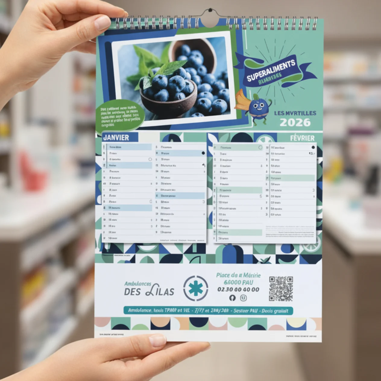Calendrier mural en main montrant janvier et février 2026 avec photo et thème des myrtilles.