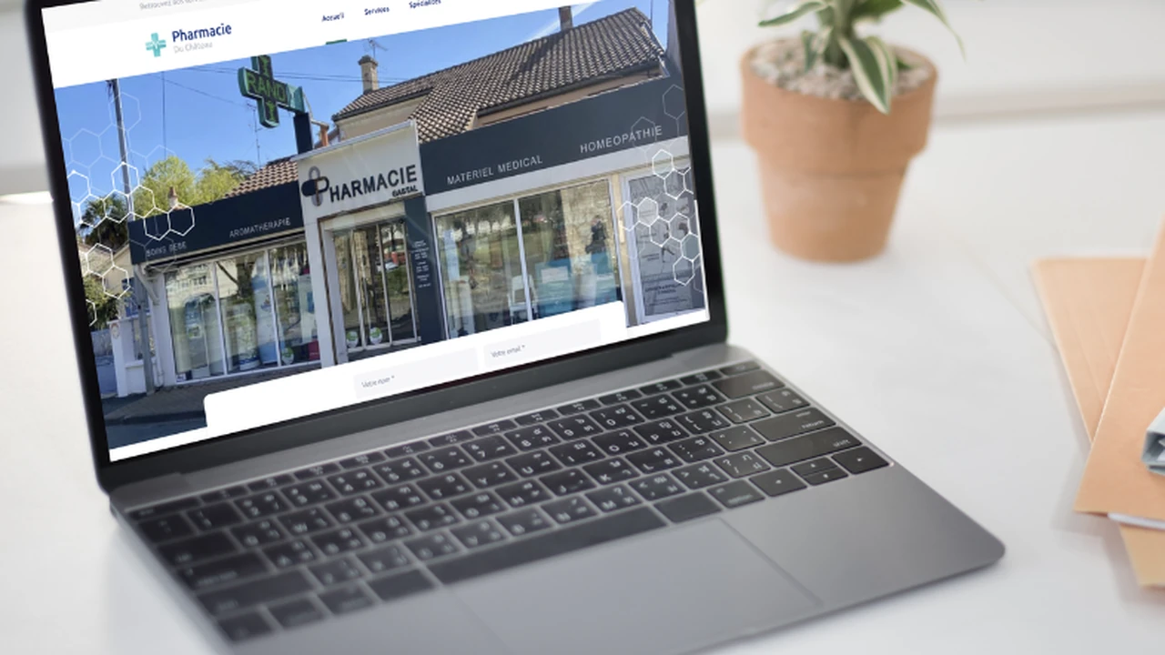 Ordinateur portable ouvert affichant un site web d'une pharmacie sur un bureau blanc avec une plante.