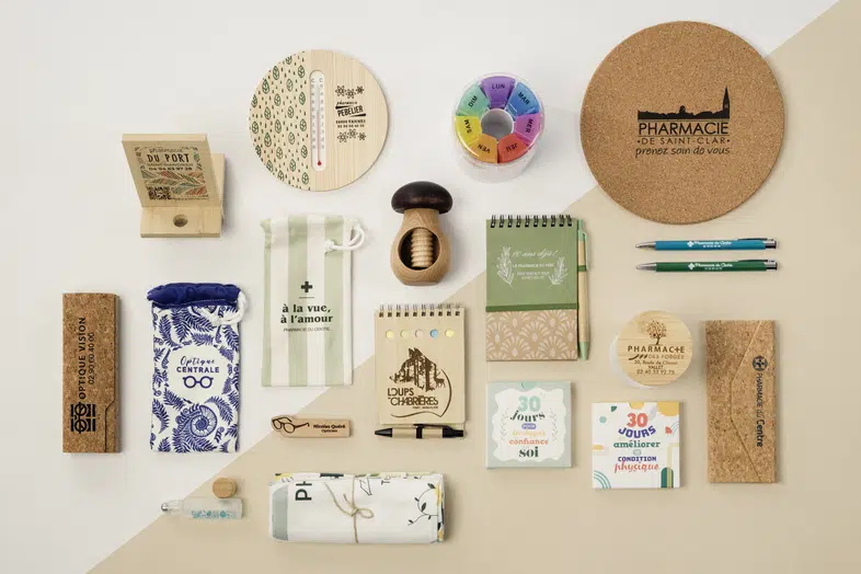 Objets personnalisés écologiques alignés sur fond clair, incluant bloc-notes, stylos, sacs et boîtes.