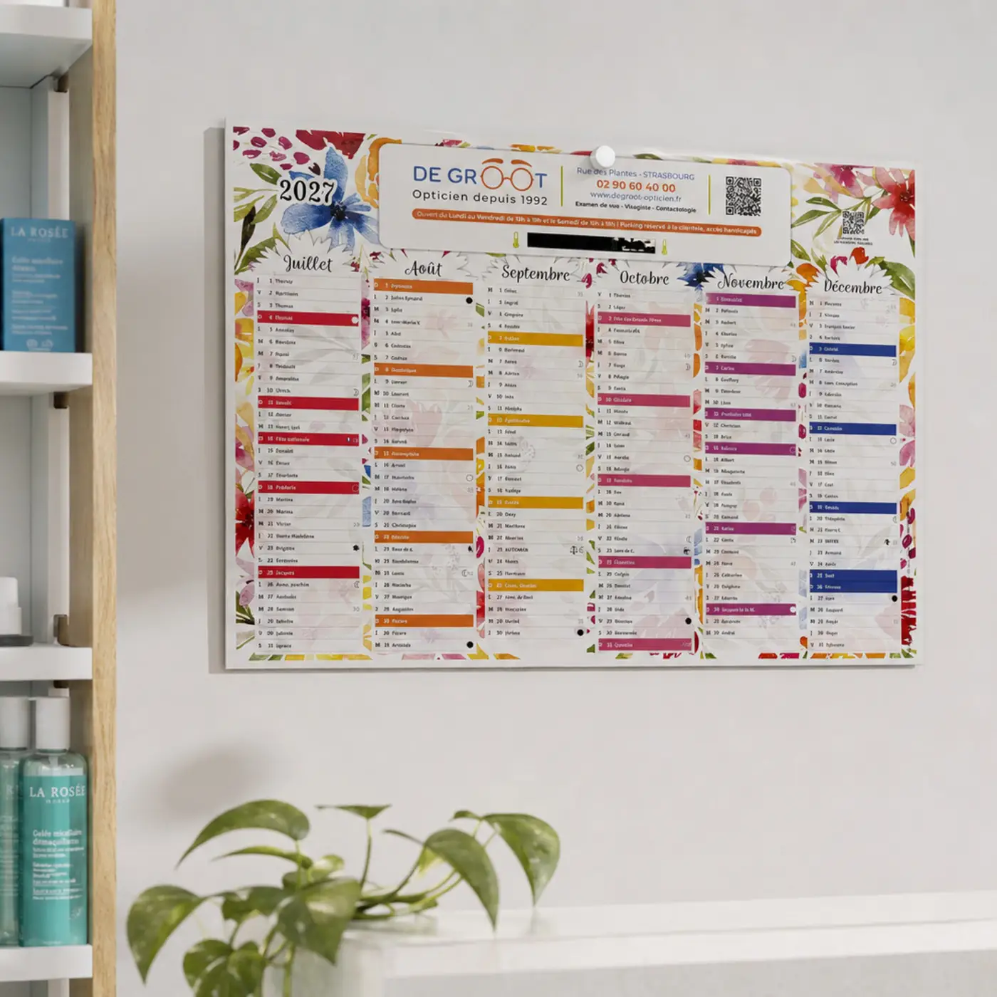 Calendrier mural 2027 avec mois de juillet à décembre et design floral accroché sur un mur blanc.