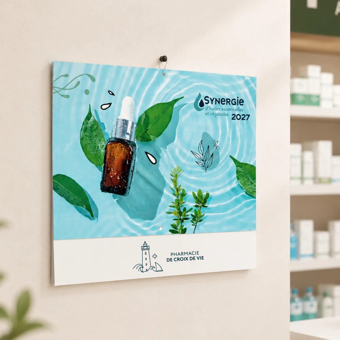 Calendrier mural avec une bouteille d'huile essentielle, feuilles et texte Synergie 2027 Pharmacie Croix de Vie.
