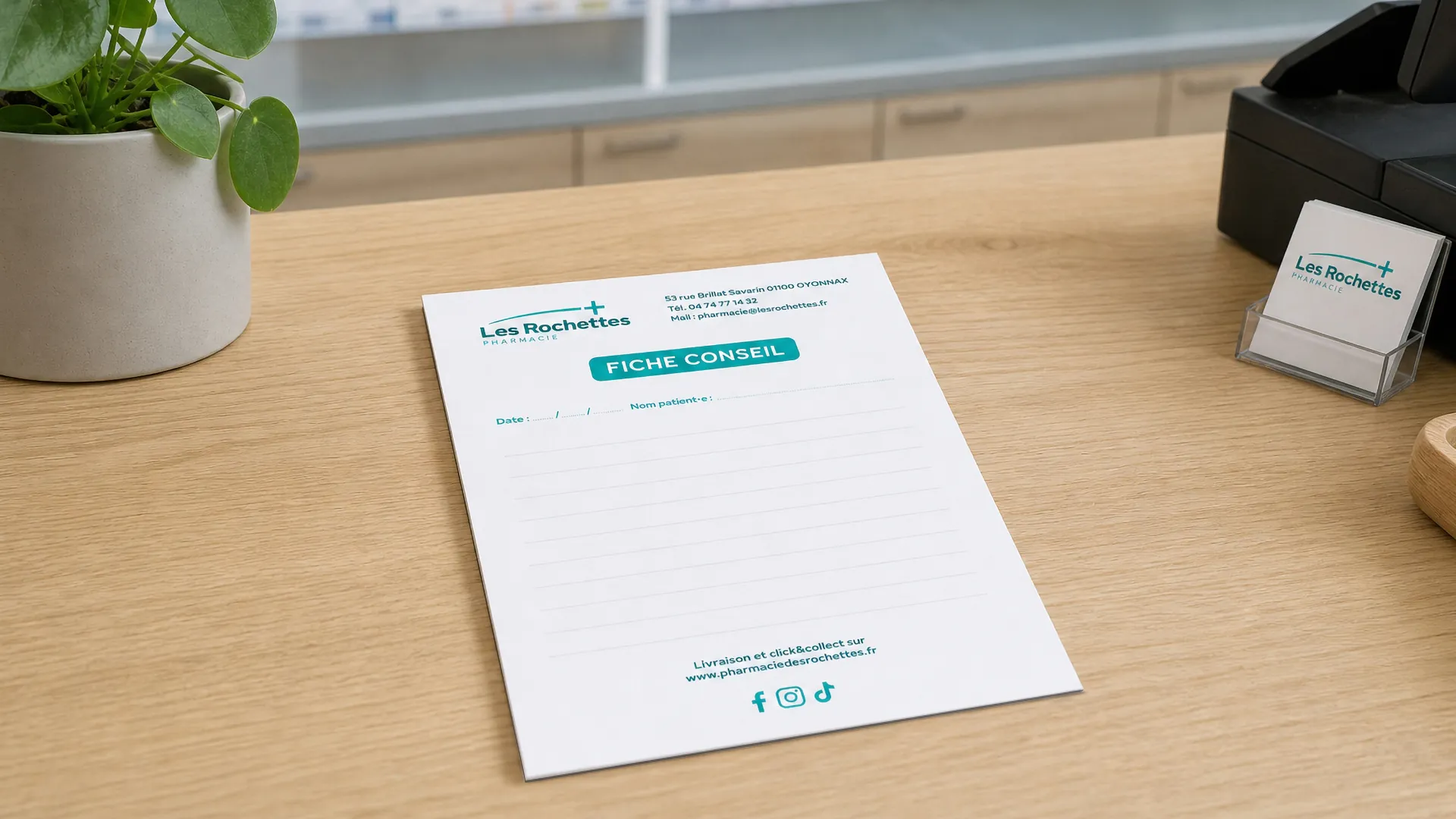 Fiche conseil de la pharmacie Les Rochettes sur un bureau en bois avec cartes de visite et plante verte.