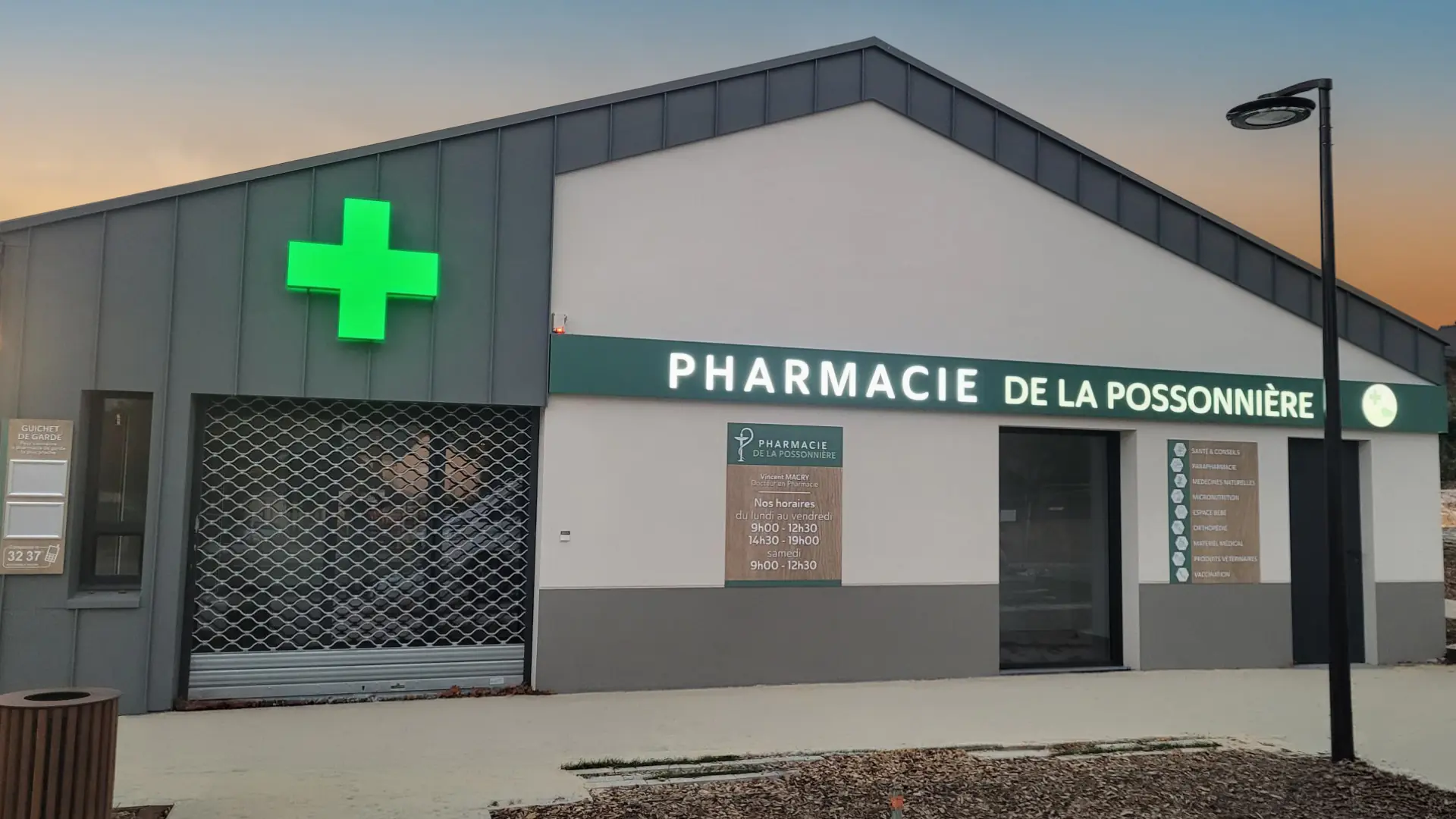 Façade de la pharmacie de la Possonnière avec une croix verte lumineuse et horaires affichés.