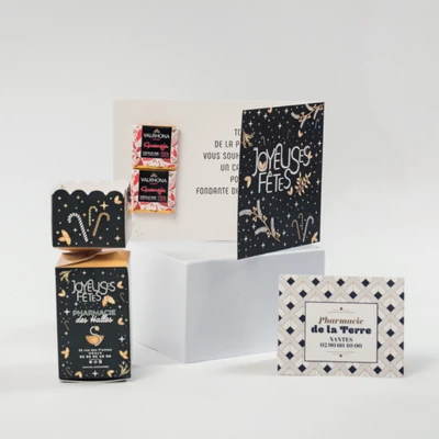 Assortiment de chocolats et cartes de vœux joyeuses fêtes sur boîte blanche.