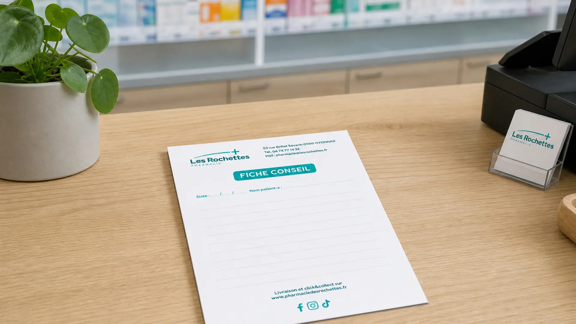 Feuille de fiche conseil de la pharmacie Les Rochettes sur un comptoir en bois avec plante et cartes.