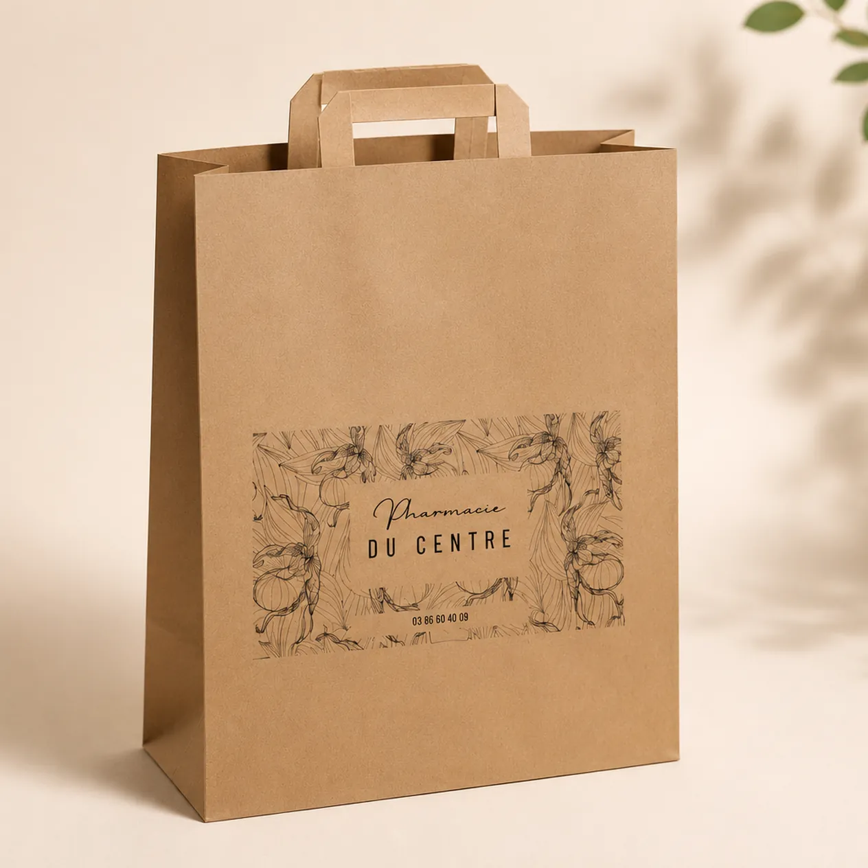Sac en papier brun avec le texte Pharmacie du Centre et un motif floral noir.
