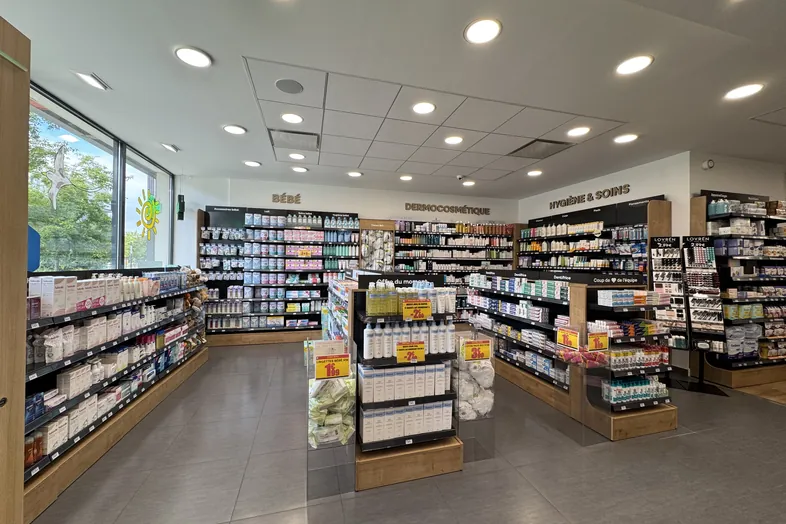 Intérieur d'une pharmacie avec des rayons de produits pour bébés, dermocosmétique et hygiène.
