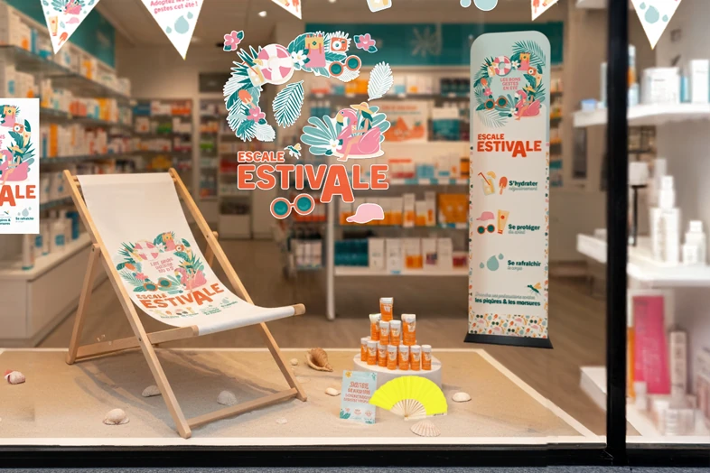 Vitrine de pharmacie avec chaise longue, crème solaire, éventail et décorations d'été colorées.