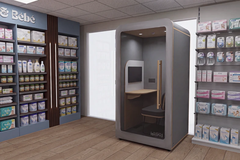 Cabine de confidentialité moderne avec siège, bureau, et écran dans un magasin de produits pour bébés.