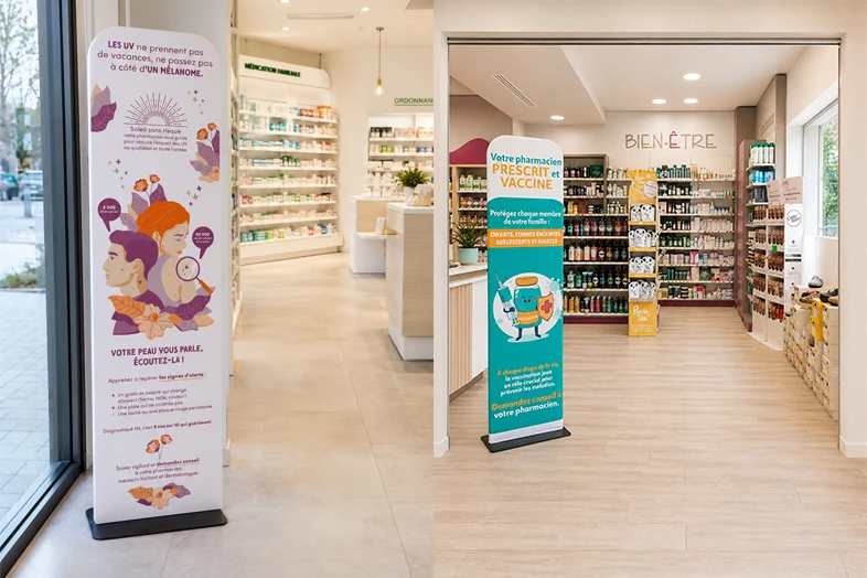 Intérieur d'une pharmacie avec deux totems d'information sur la peau et la vaccination.