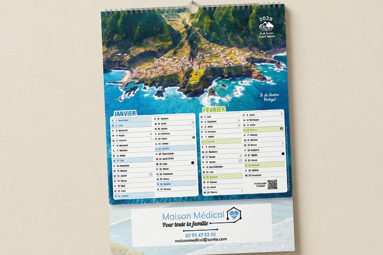 Calendrier mural 2028 avec photo aérienne d'un village côtier, janvier et février visibles en français.