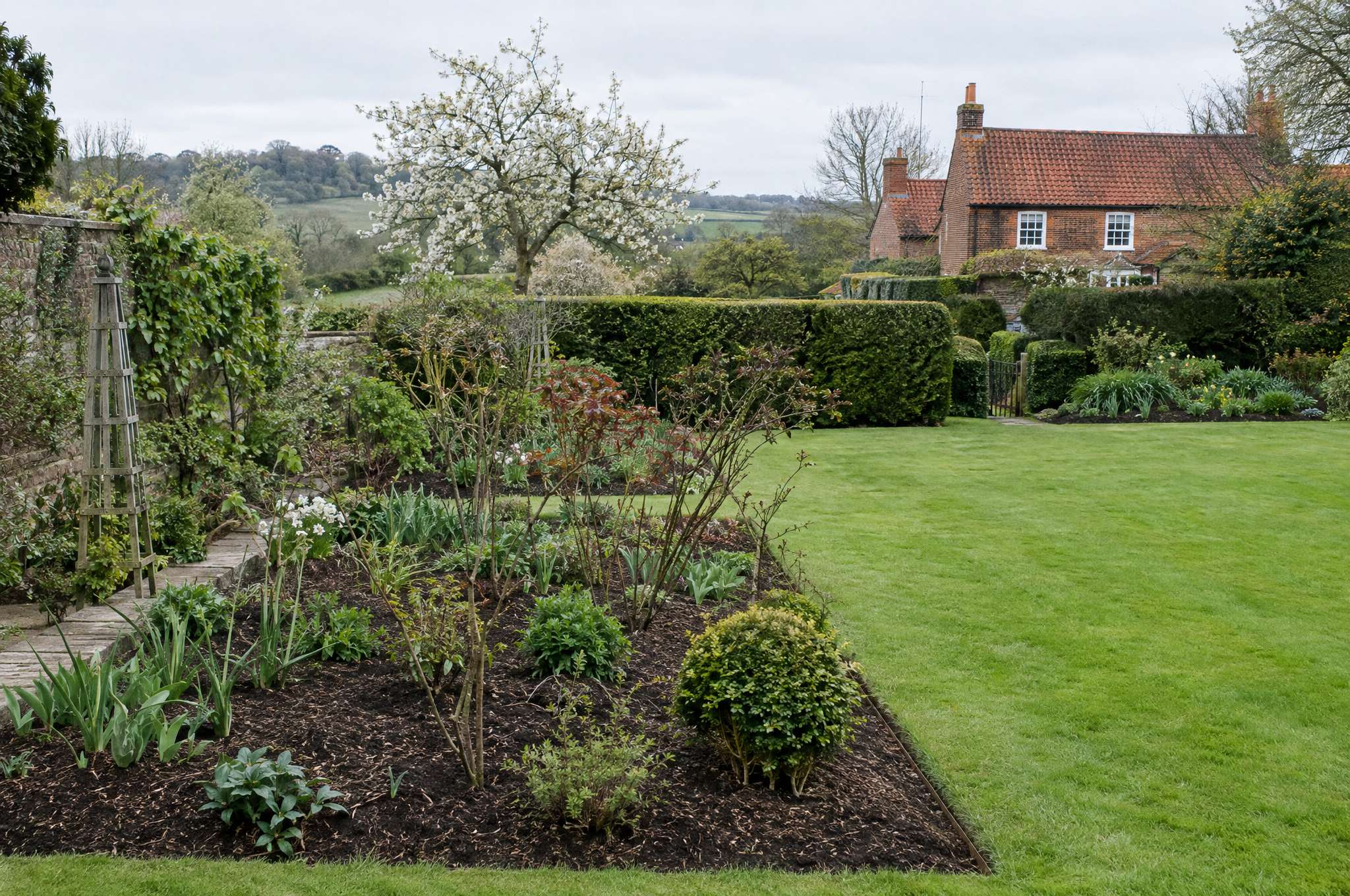 Spring garden freshly reset, beds open and mulched with the first growth coming through