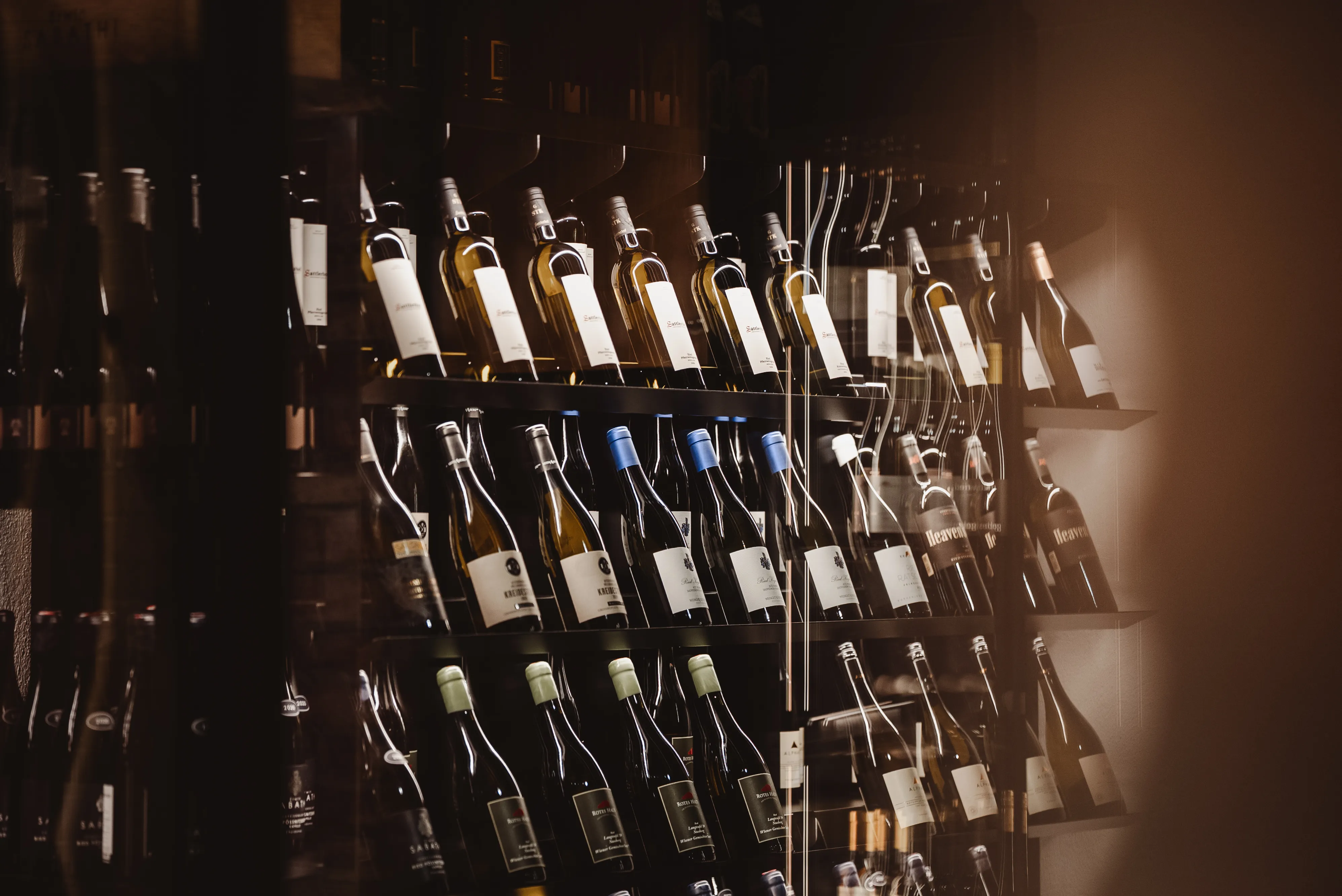 Shelves filled with various wine bottles arranged in rows with different colored caps.