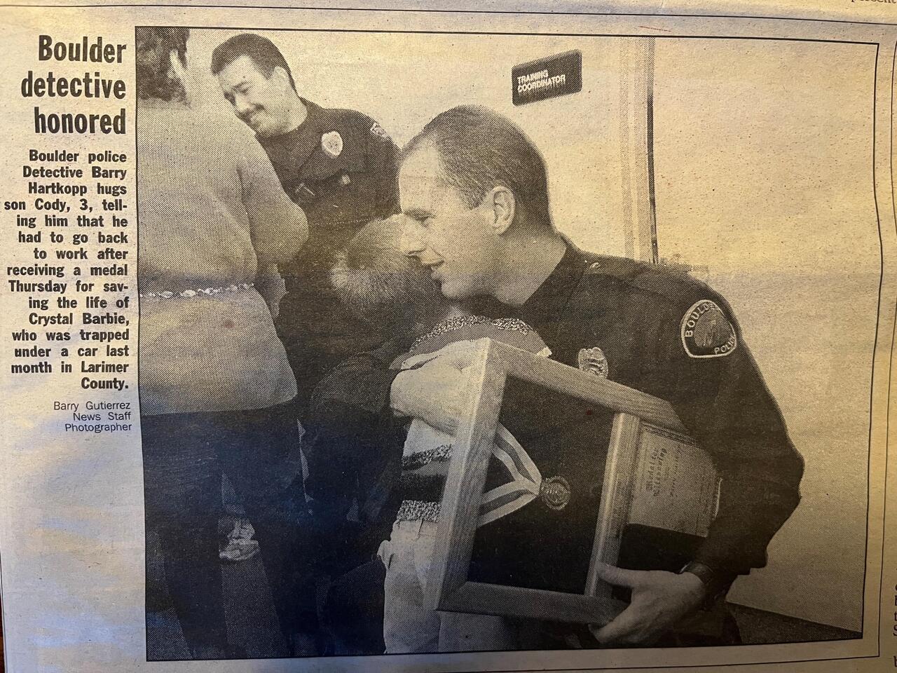 A newspaper photo shows then Detective Barry Hartkopp hugging his son Cody after receiving an award.