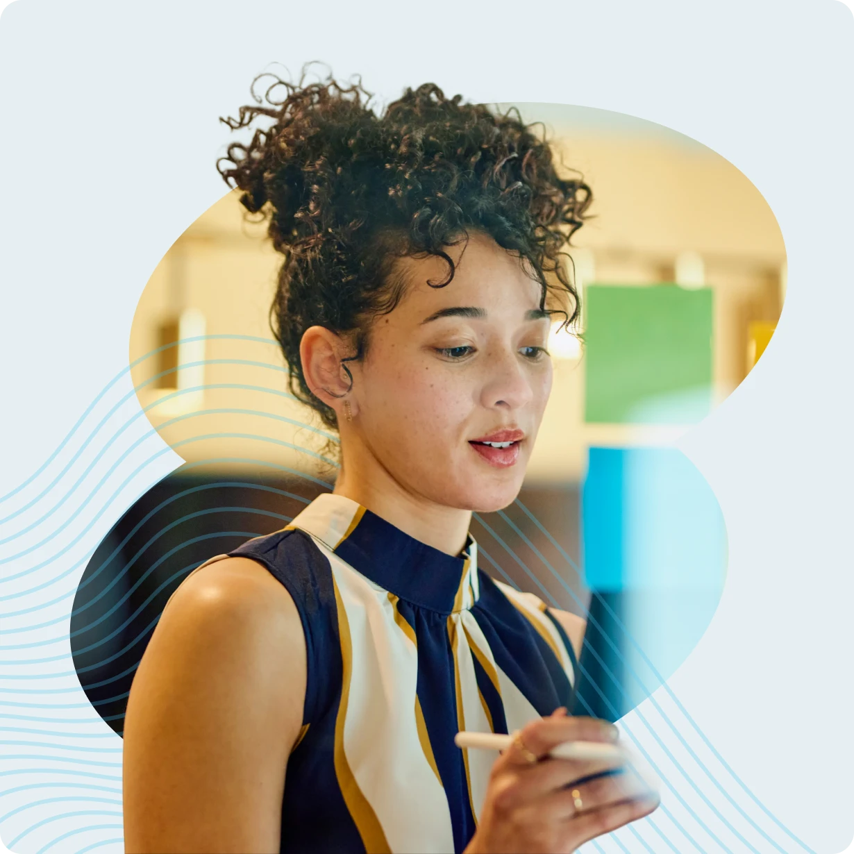 Woman with curly hair wearing a striped sleeveless top looks at a smartphone, holding a stylus pen.
