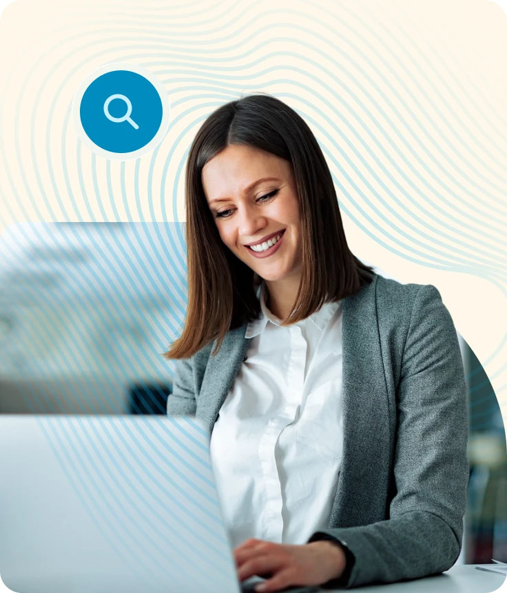 Smiling woman in gray blazer working on a laptop with a blue search icon above her head.