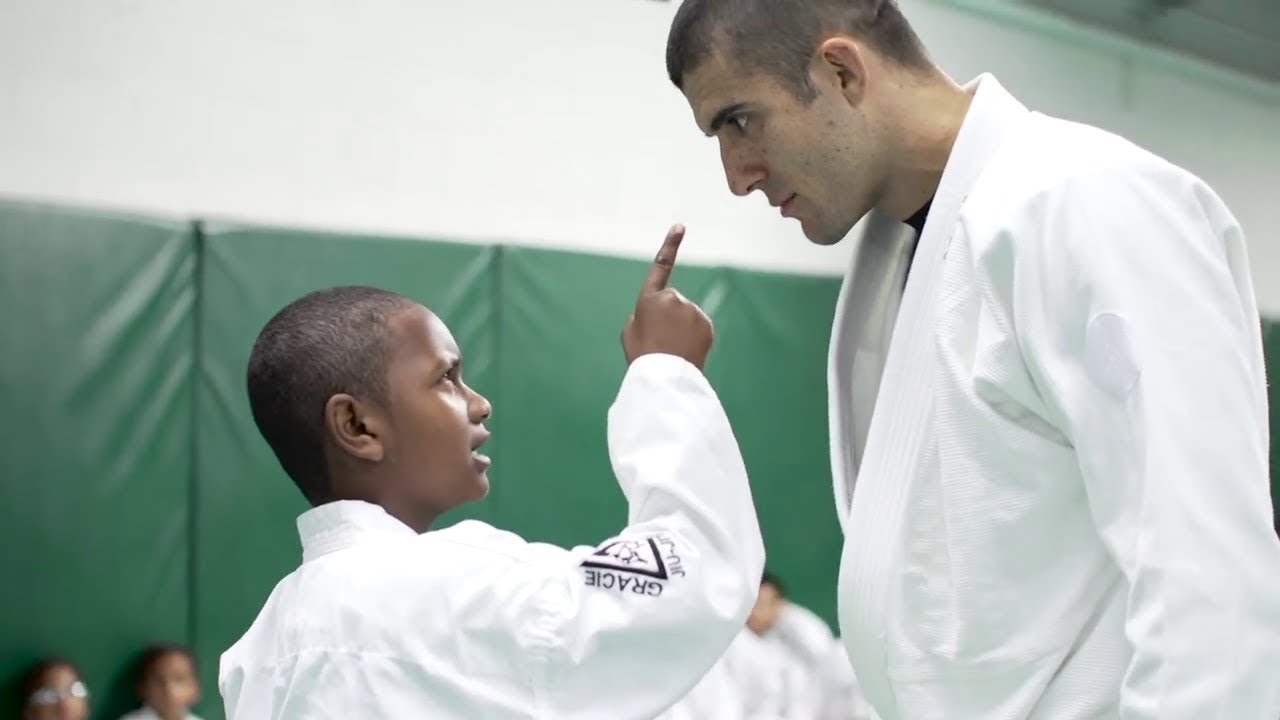 Video still: Gracie instructor talking with a young student in a white gi