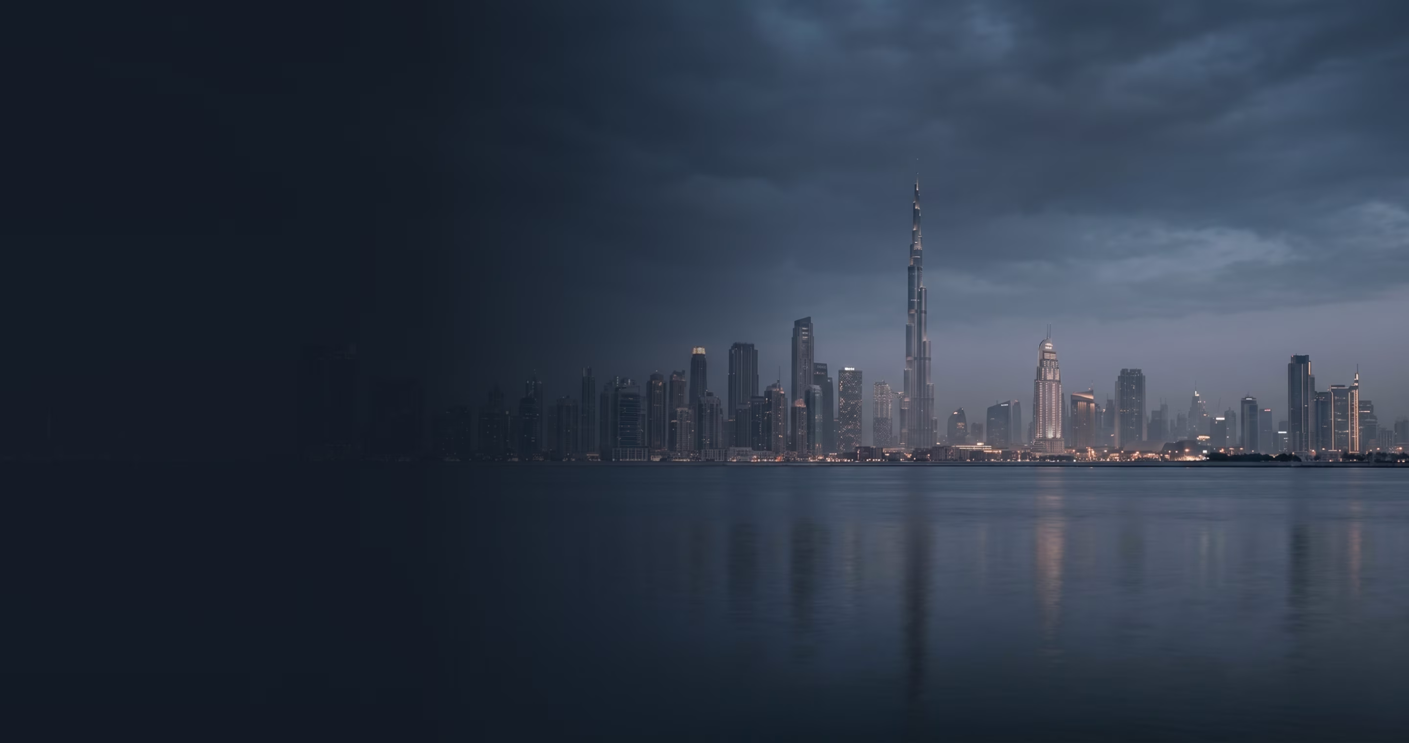 City skyline at dusk with tall buildings reflected on calm water under cloudy sky.