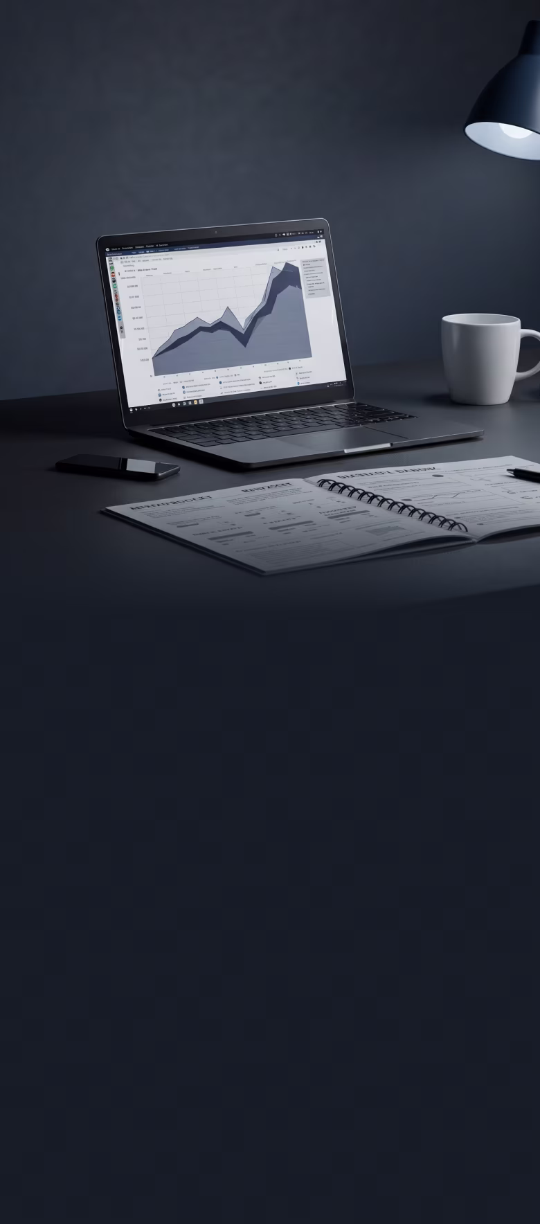 Laptop on desk displaying a rising area chart, with a smartphone, open planner, coffee mug, and desk lamp nearby.