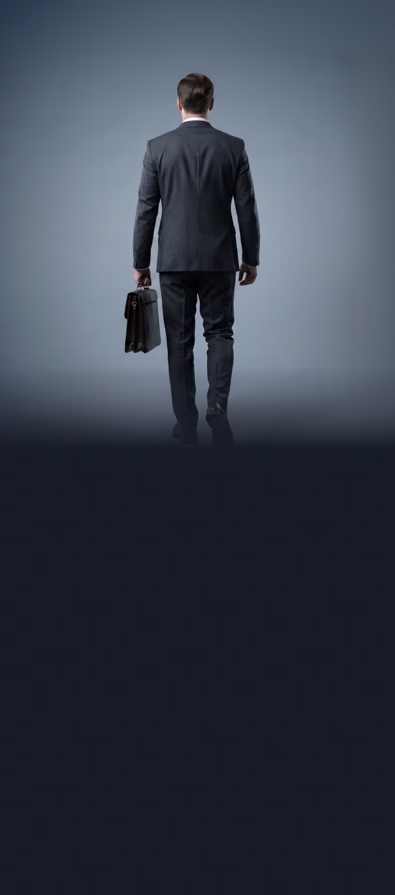 Man in a dark suit holding a briefcase, walking away against a plain gray background.