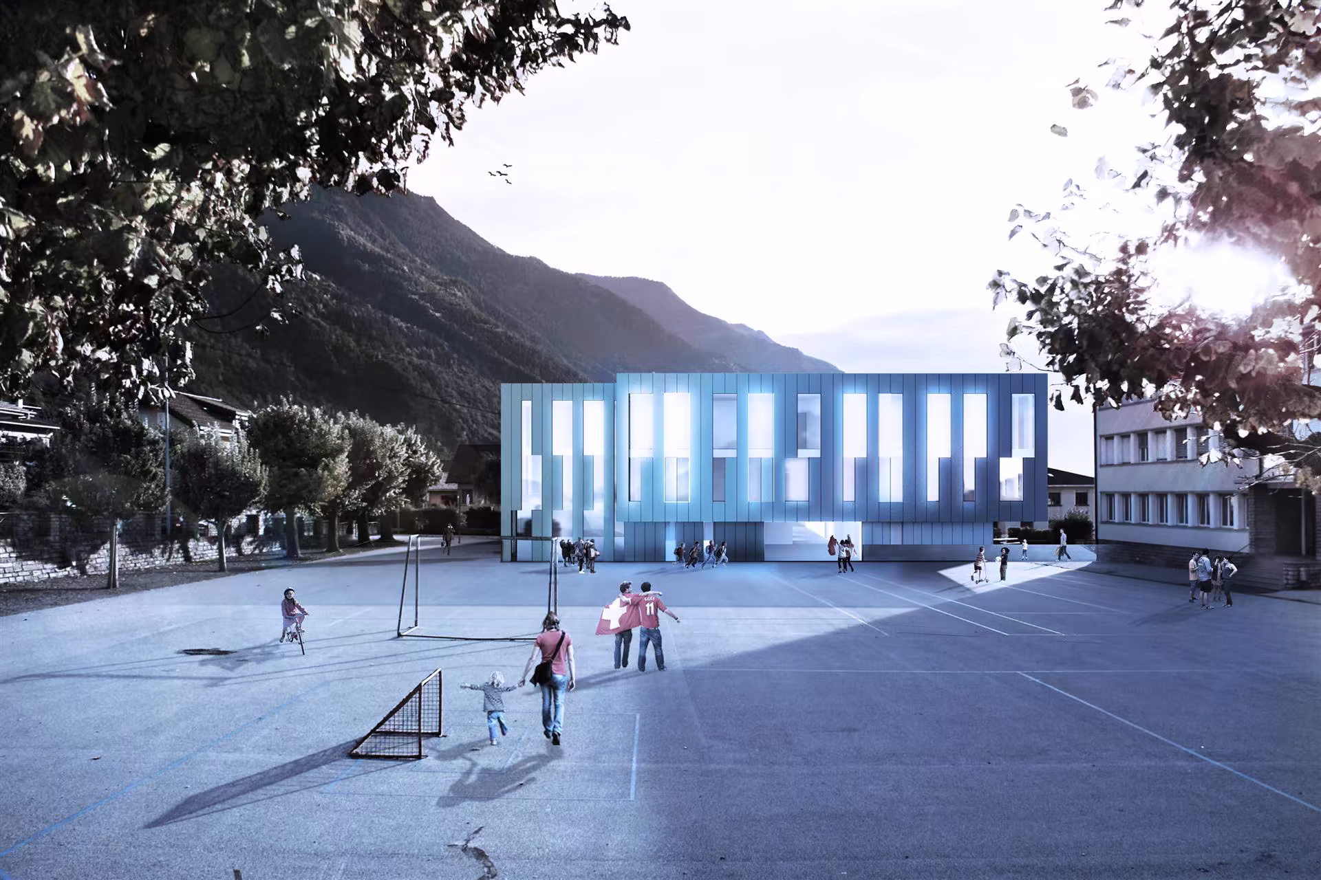 Cour de récréation avec enfants et adultes, devant un bâtiment moderne à plusieurs fenêtres, entouré de montagnes et d'arbres.