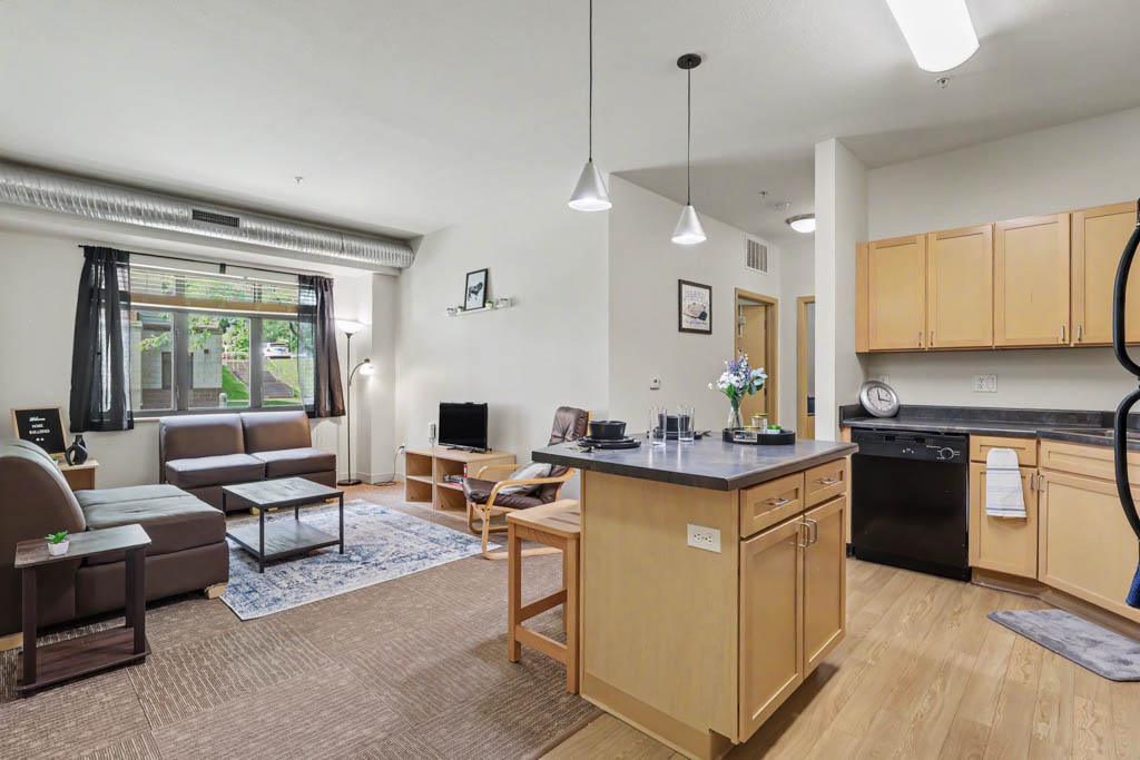 Living area with sofa, with view of kitchen and desk area in bedroom