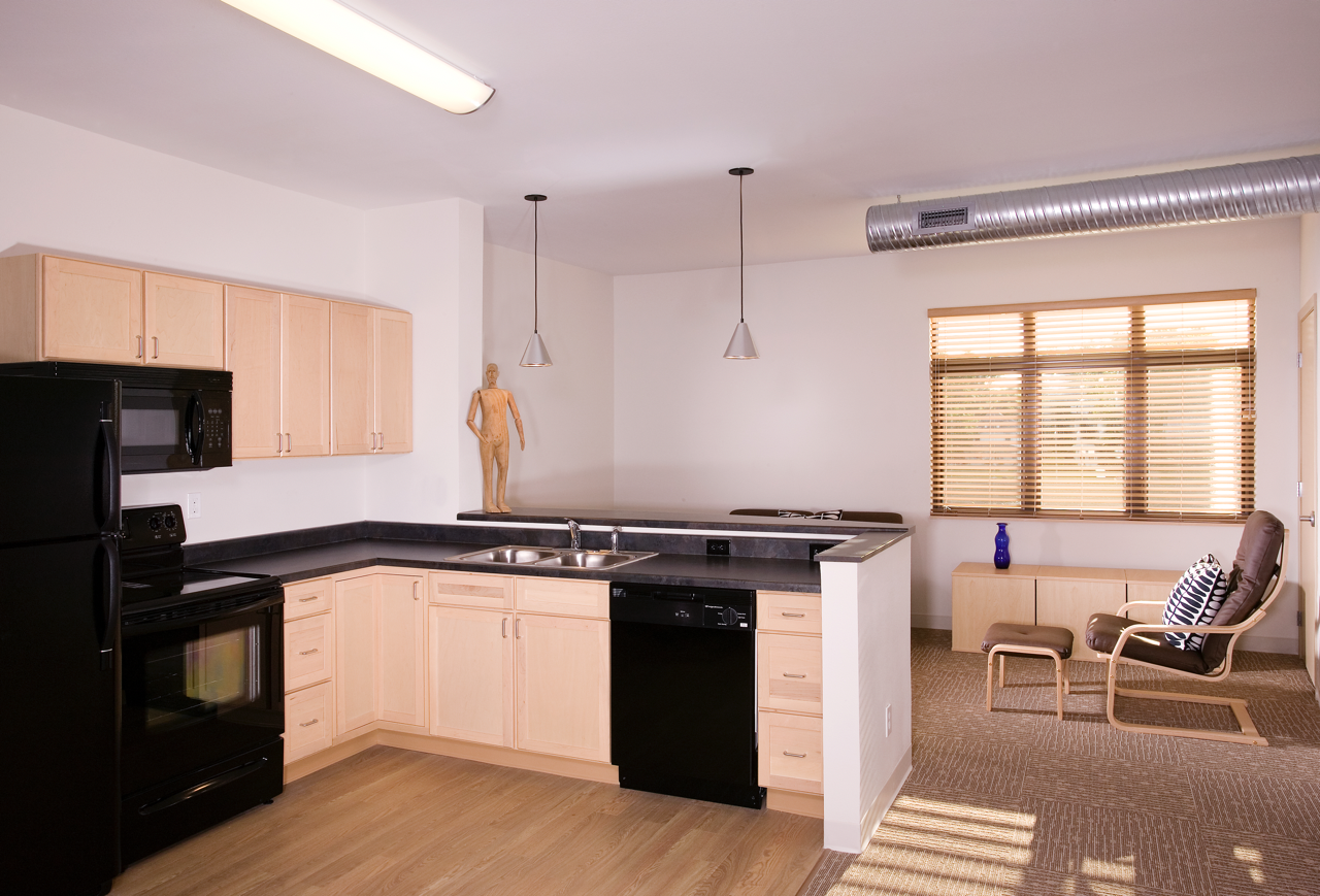 Kitchen with black appliances and view into living area with large window