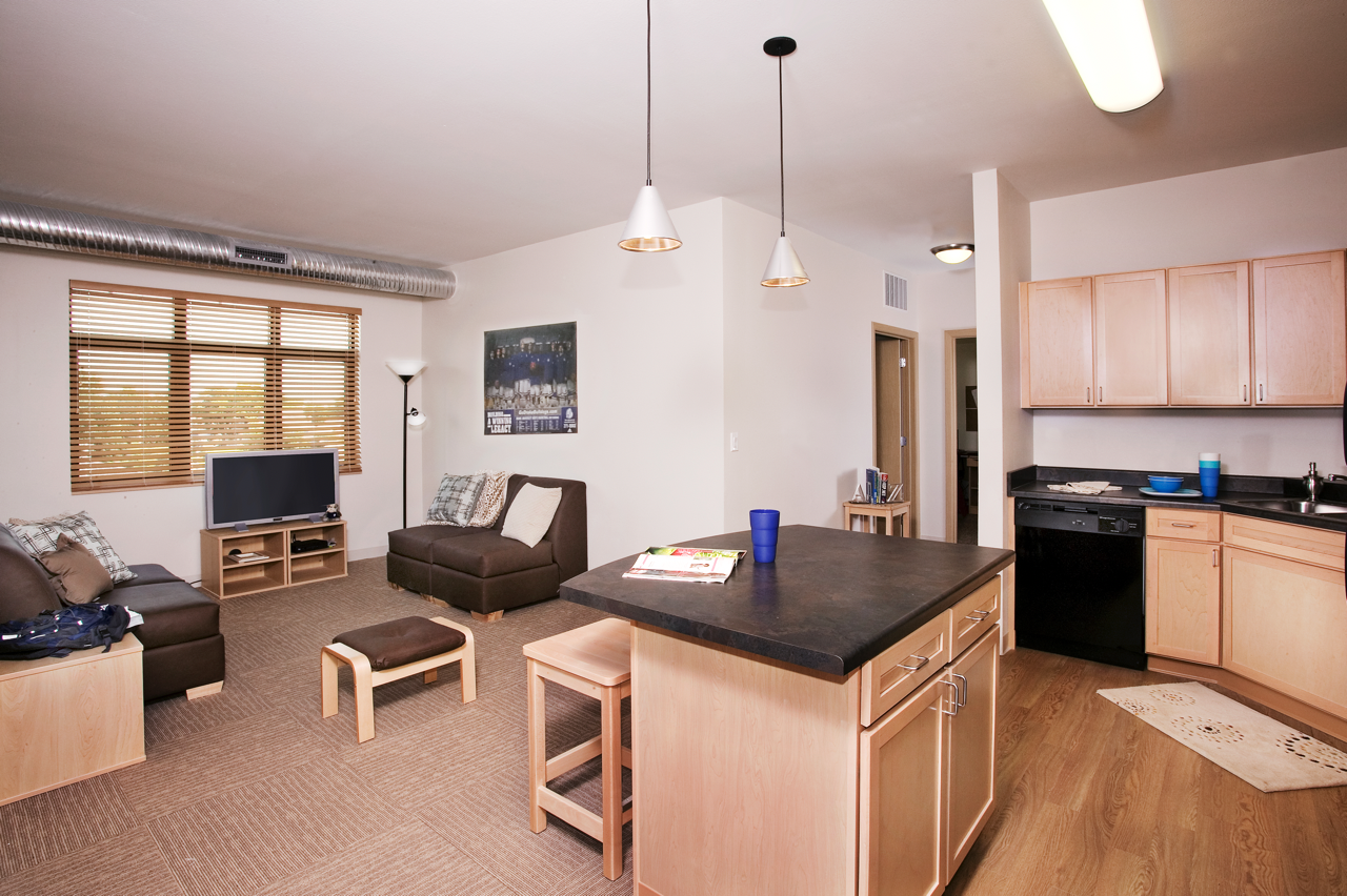 Living area with chair, and view of Kitchen with black appliances and breakfast bar with chairs