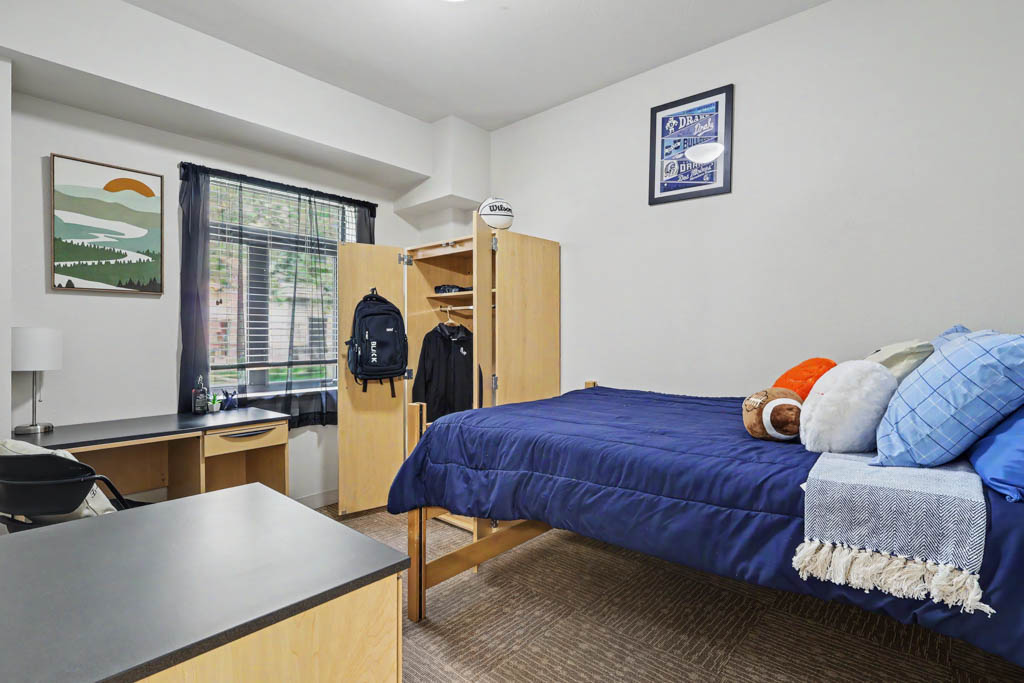 Bedroom with bed, desk and Drake University decor