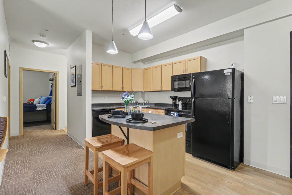 Wiew of Kitchen with black appliances and breakfast bar with chairs