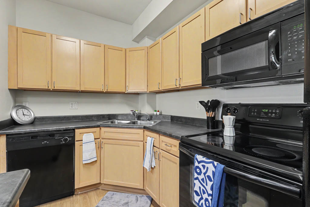Kitchen with black appliances and view into living area with large window