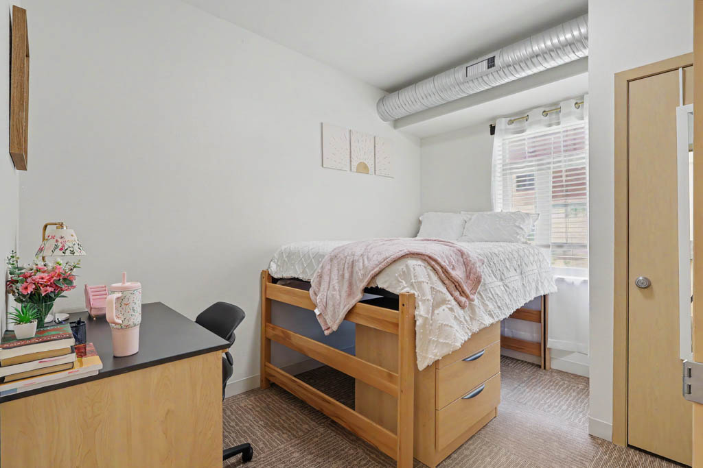 Bedroom with bed, desk, large window and wardrobe