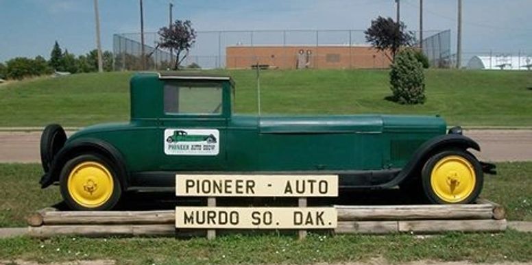Green vintage car with yellow wheels and signs reading Pioneer Auto Murdo So. Dak.