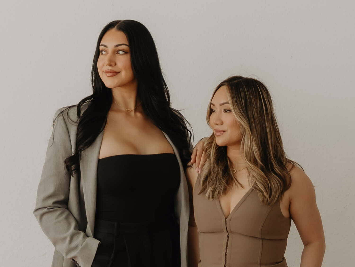 Four diverse women posing and smiling in a light-filled room with wooden floors and curtains.